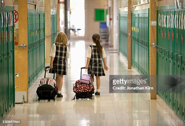 second grade girls roll backpacks in school. - school uniform stock pictures, royalty-free photos & images