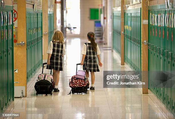 second grade girls roll backpacks in school. - uniforme escolar - fotografias e filmes do acervo