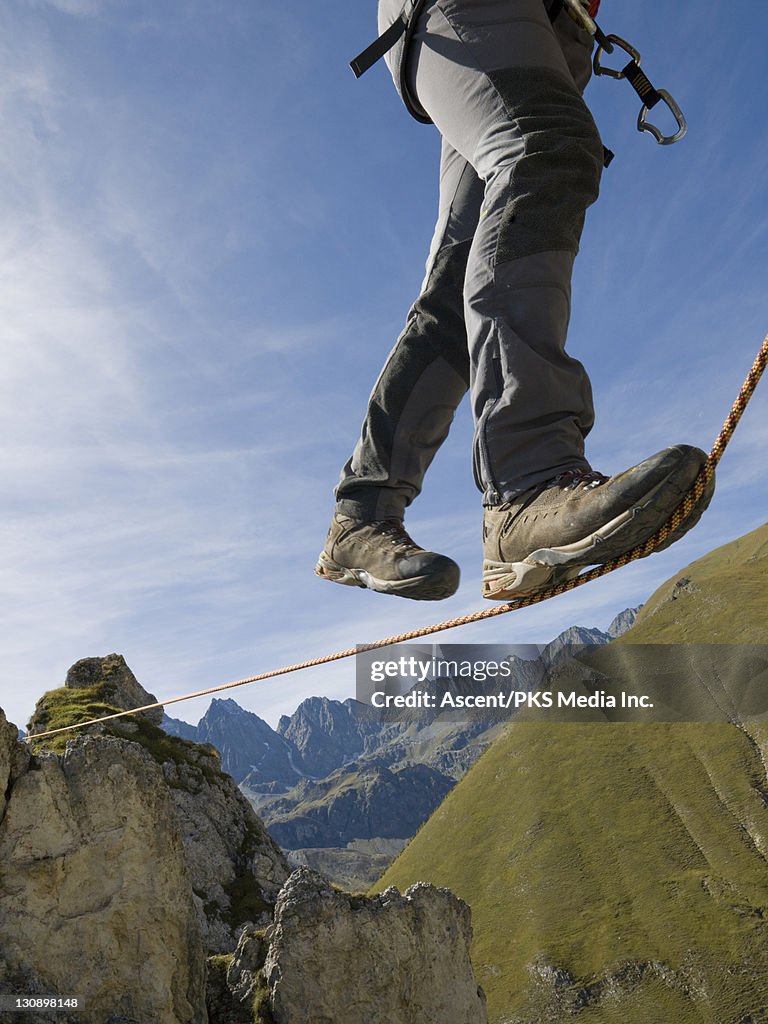 Climber traverses rope stretched over mtns, valley