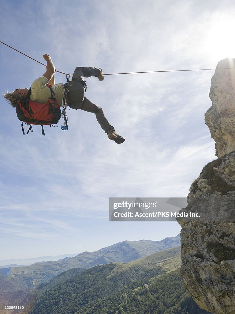 Climber crosses gap above mtns, Tyrolean Traverse