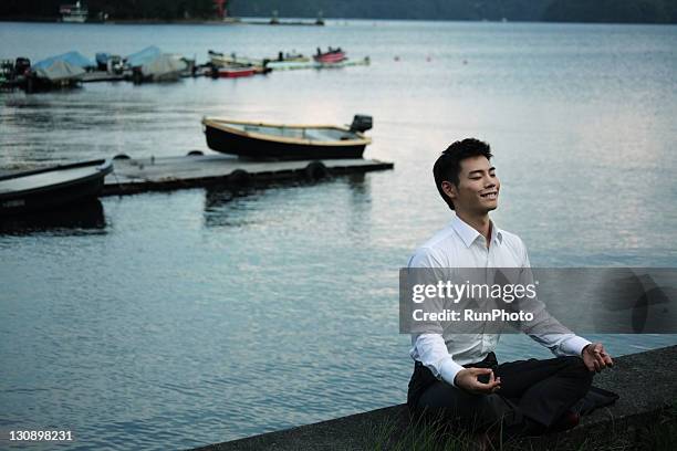 young businessman doing yoga in the lake - east asia ストックフォトと画像