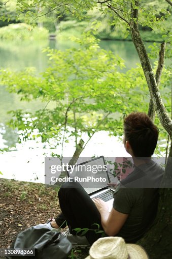 Young man with a Notebook PC in the forest Young man with a Notebook PC in the forest