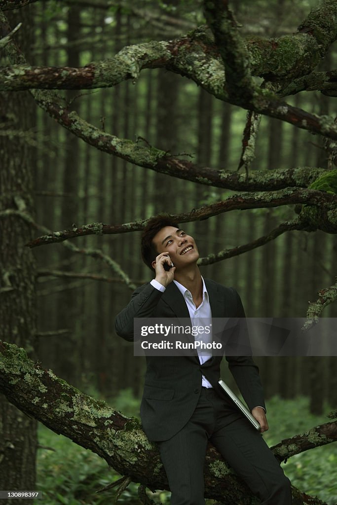 Businessman talking on mobile phone in the forest