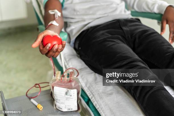 la mano de un donante de sangre exprimiendo una pelota de goma médica - banco de sangre fotografías e imágenes de stock