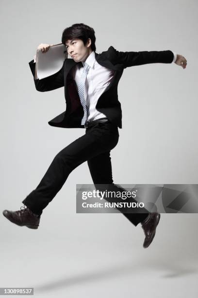 young businessman running with a binder - running midair stock pictures, royalty-free photos & images