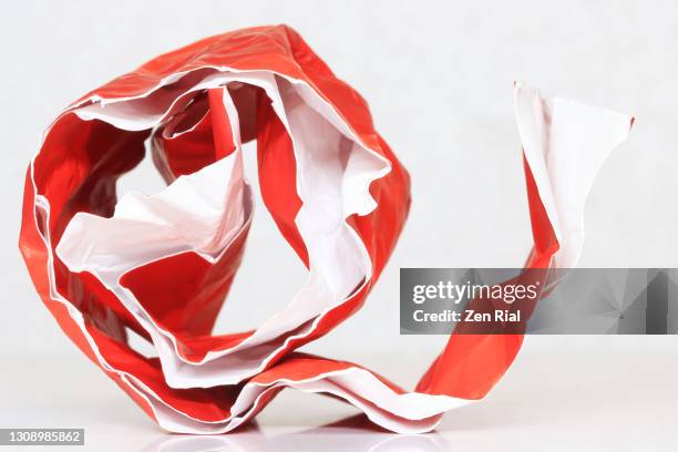 glossy red paper folded creased and rolled against white background - roll of wrapping paper stock pictures, royalty-free photos & images