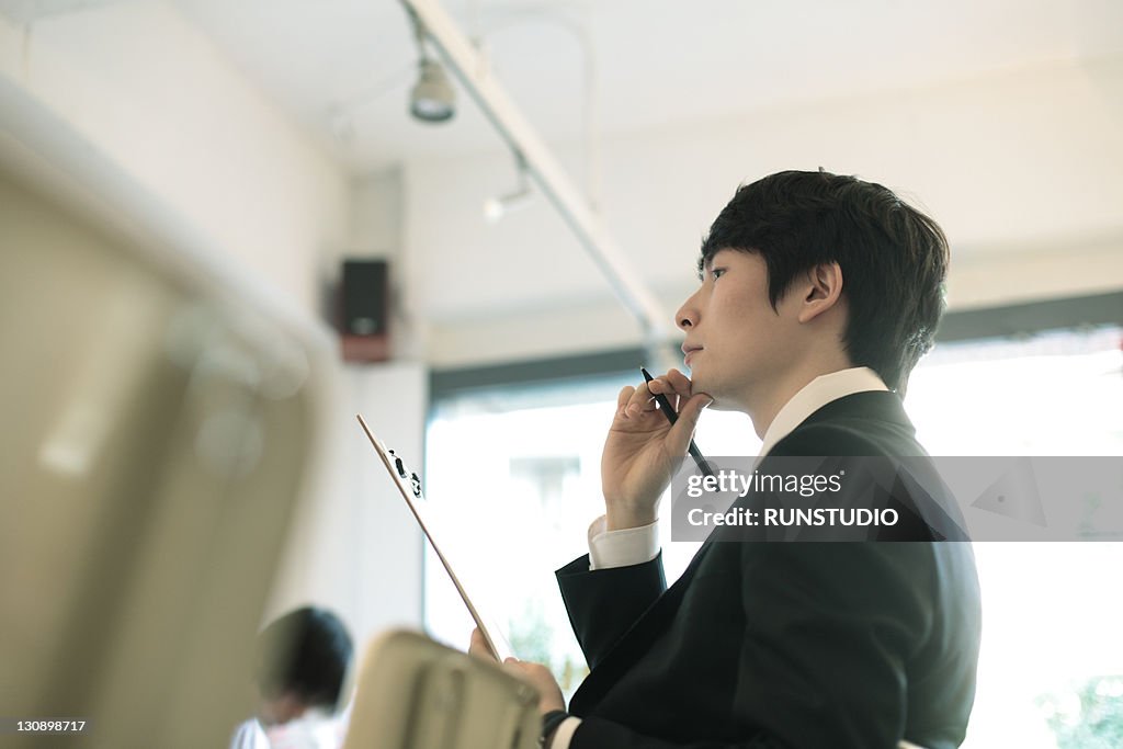 Young businessman thinking with a pen