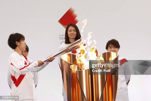 Azusa Iwashimizu , member of Japan women's football national team, lights the torch from the celebration cauldron during the Tokyo 2020 Olympic Torch...