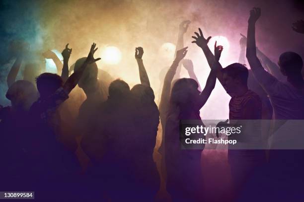 crowd of people at concert waving arms in the air - nightclub stockfoto's en -beelden