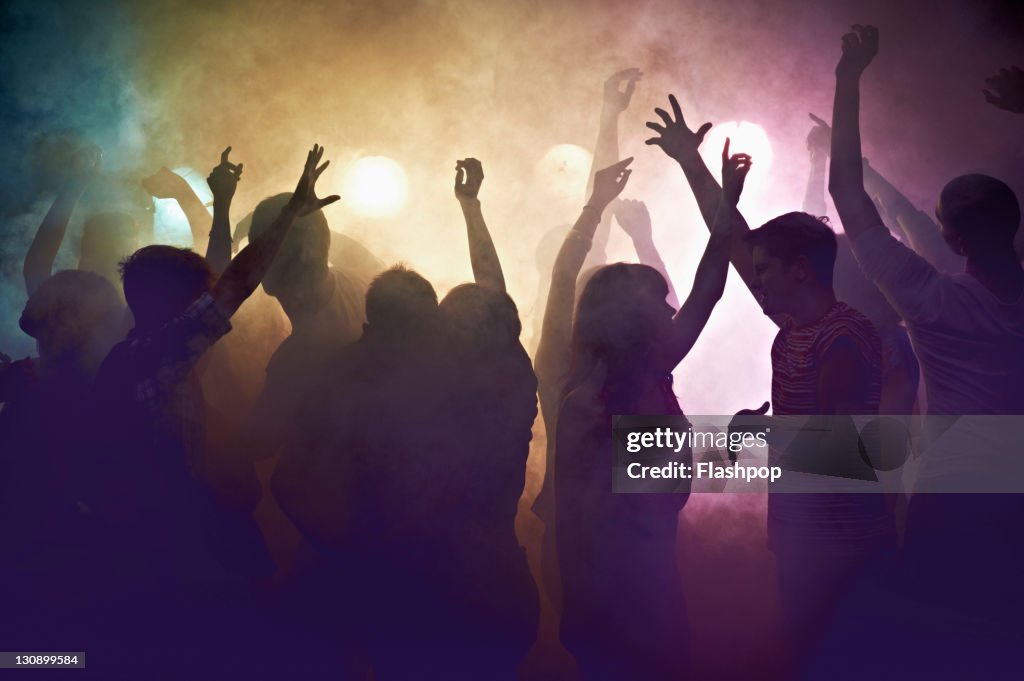 Crowd of people at concert waving arms in the air