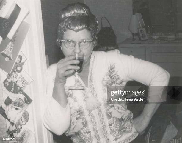 funny grandmother wearing wig and drinking alcohol at holiday party 1950s vintage photograph - 1950 1959 mode stock-fotos und bilder