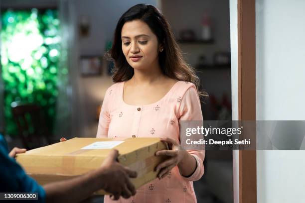 young woman receiving a package from delivery man at home. stock photo - home delivery stock pictures, royalty-free photos & images