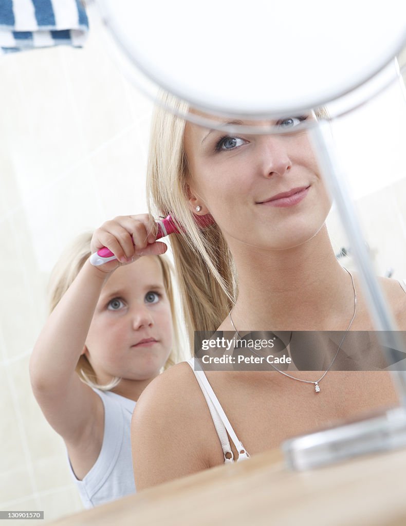 Daughter brushing mothers hair in bathroom