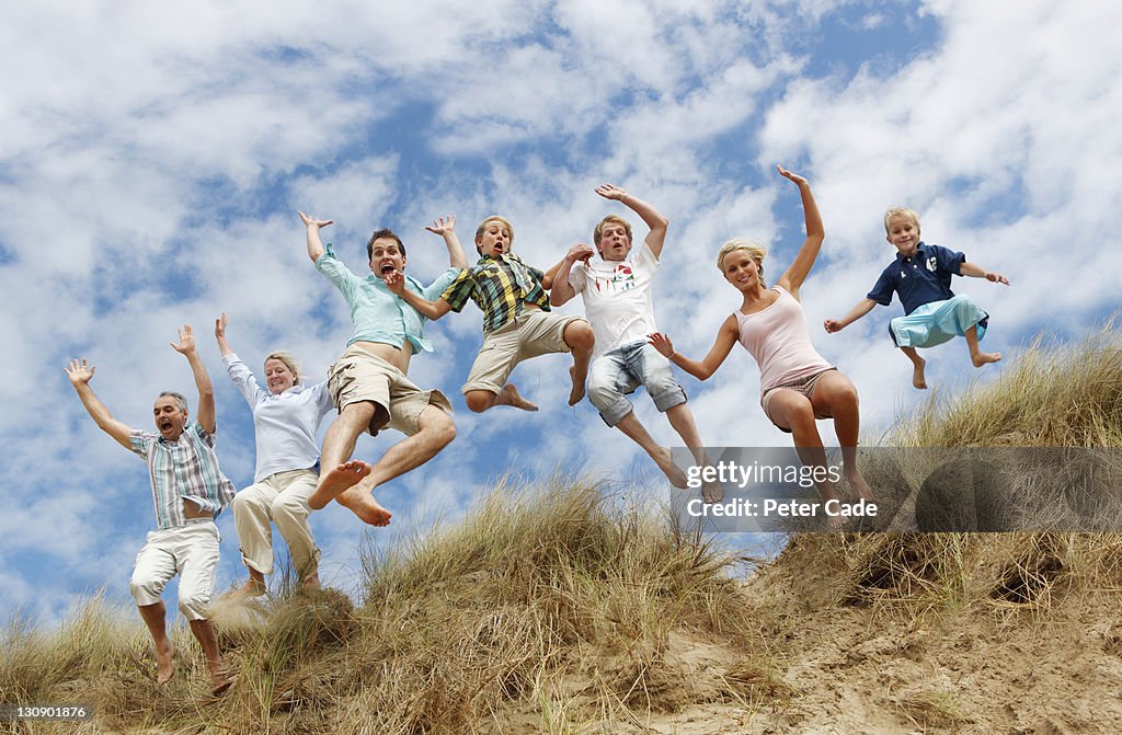 Large family jumping from sand dunes