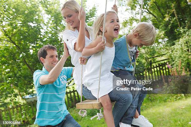 family playing on tree swing - family garden play area photos et images de collection