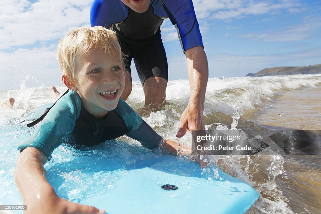 Fther helping son to bodyboard