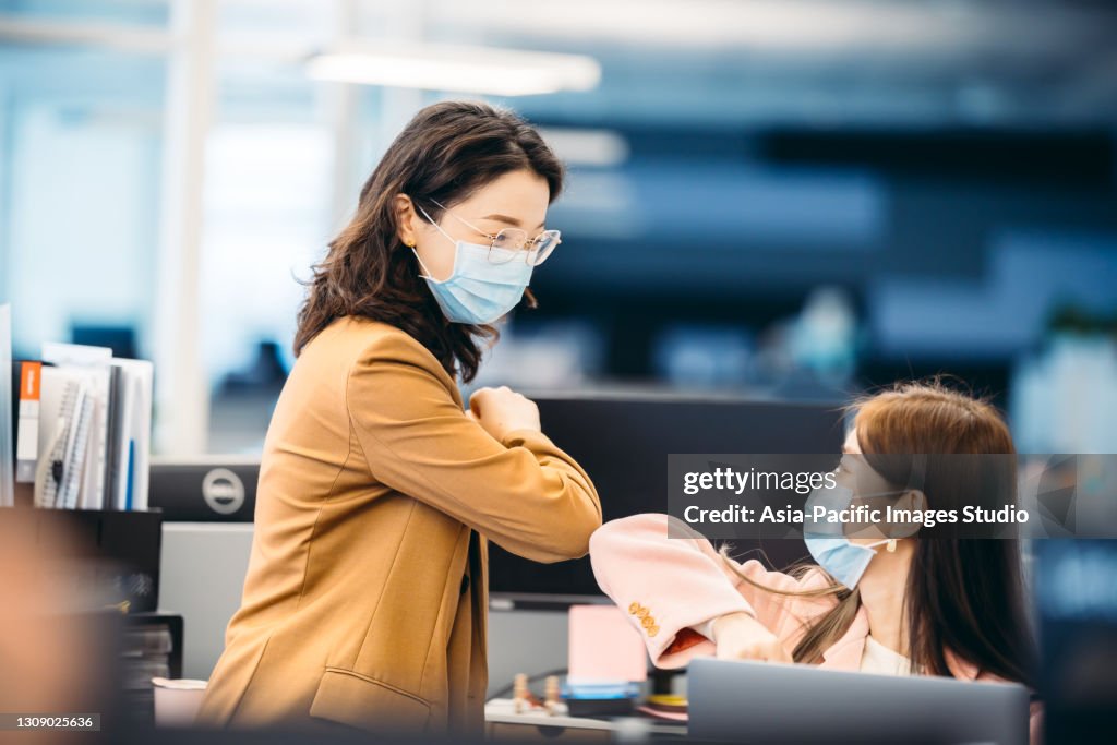 Asian young businesswomen working together and greeting during COVID-19 pandemic, elbow bump.