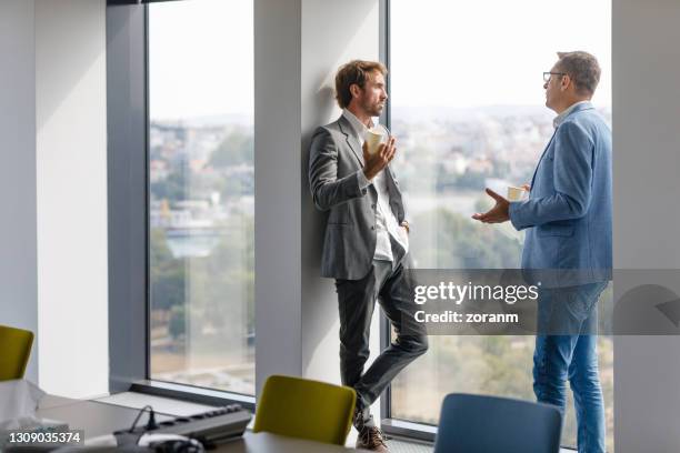 colleagues seriously discussing business on coffee break by the window - man made object stock pictures, royalty-free photos & images