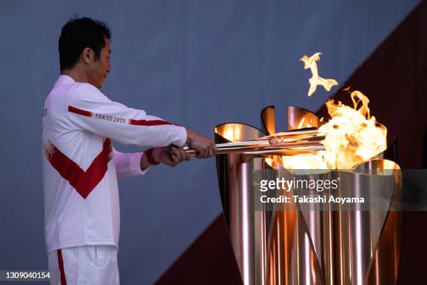 Last torch bearer of Day 1, aerobatics pilot Yoshihide Muroya lights the cauldron at Hibarigahara field during the Tokyo Olympic Games torch relay on...