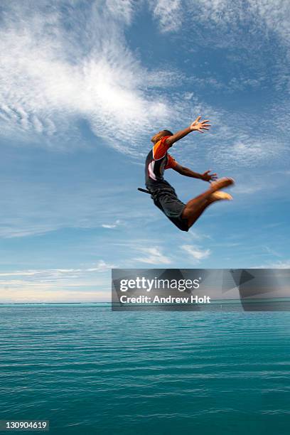 man jumping into sea from mana island pier fiji - melanesia stock pictures, royalty-free photos & images