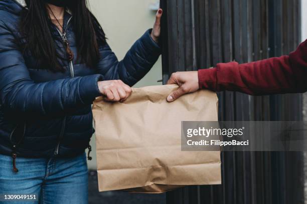 delivery man is delivering a lunch box to a woman - close up view - take away food courier stock pictures, royalty-free photos & images
