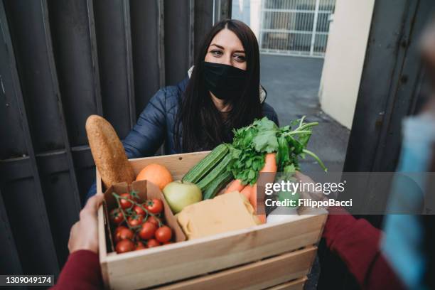 de bezorger levert fruit, groenten en kruidenierswaren aan een vrouw - doorgeven stockfoto's en -beelden