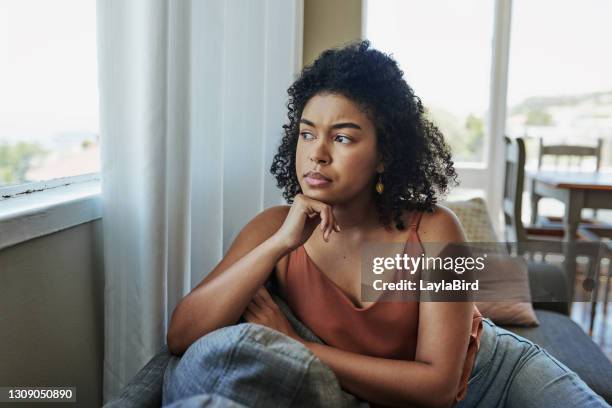 mit den sorgen einer ungewissen zukunft sitzen - stressed young woman sitting on couch stock-fotos und bilder