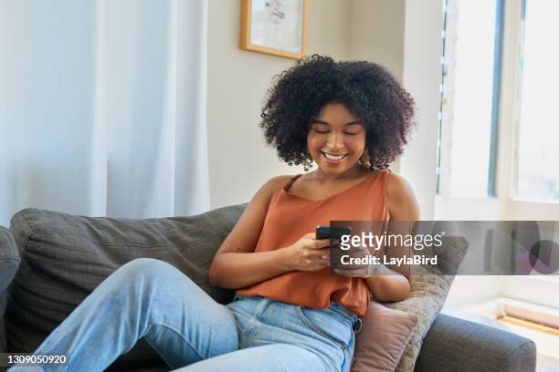 clocking high scores on her favourite mobile games - female sitting on sofa stock pictures, royalty-free photos & images