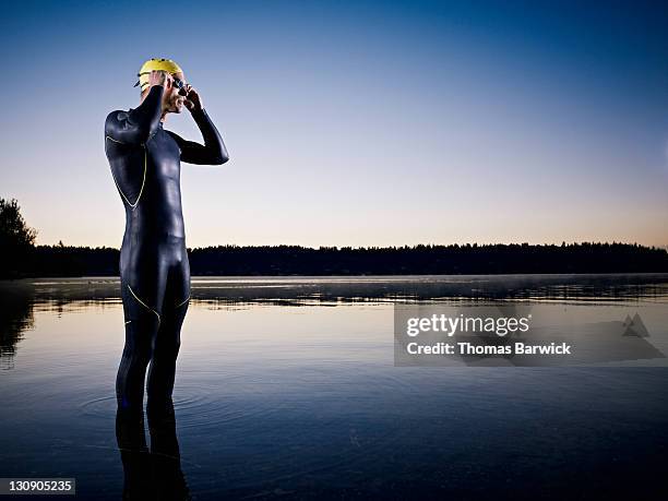 male triathlete preparing for swim at sunrise - beginner triathlon stock pictures, royalty-free photos & images