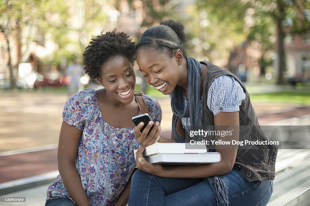 Teen Girls Sitting Outdoors using Smart Phone