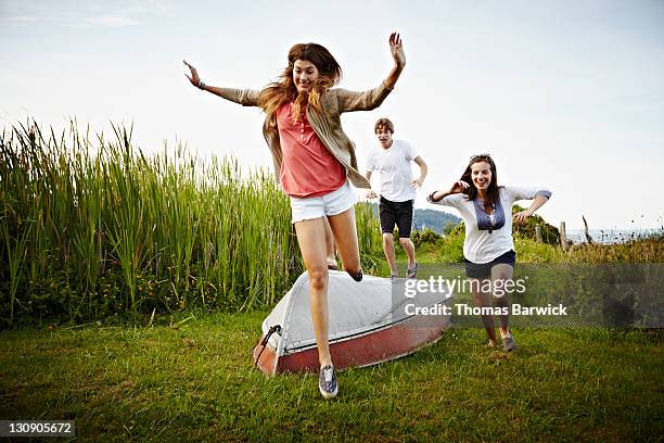 group of friends running and jumping over boat - reed grass family stock-fotos und bilder