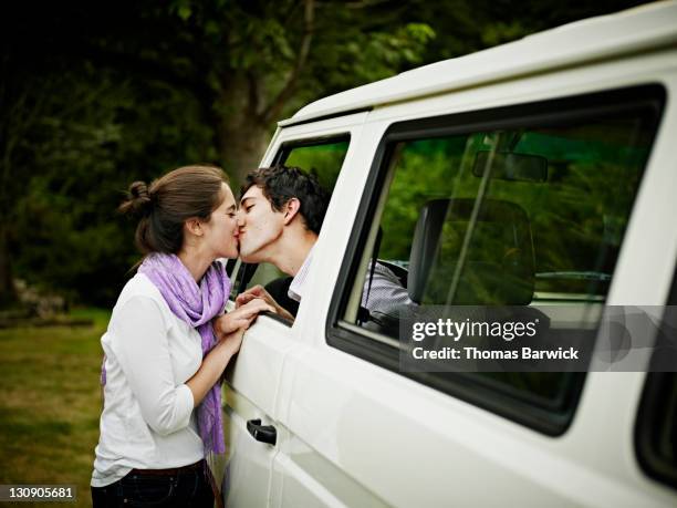 young couple leaning through window of van to kiss - auto küssen stock-fotos und bilder