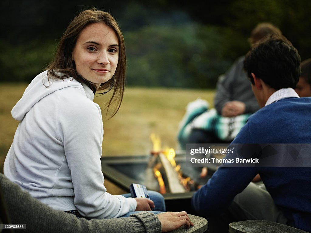 Portrait woman sitting next to fire with friends