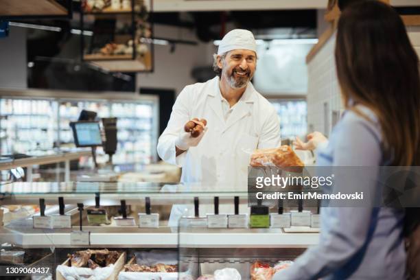 cliente donna che sceglie la carne dal banco gastronomia al supermercato - macellaio foto e immagini stock