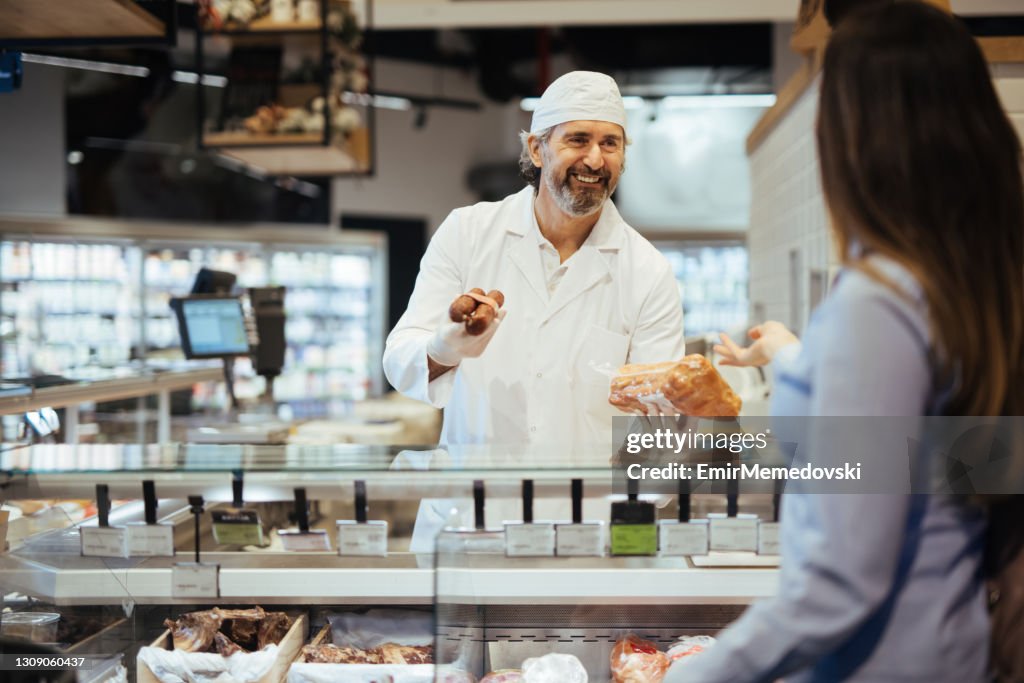 Female customer choosing meat from deli counter in supermarket