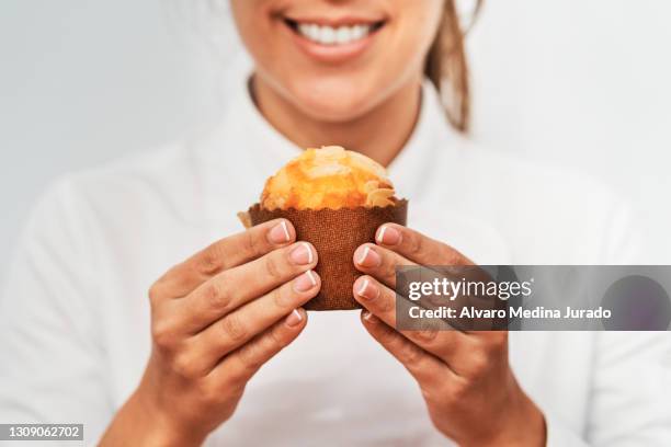 happy confectioner showing delicious freshly baked sweet muffin - muffin stockfoto's en -beelden