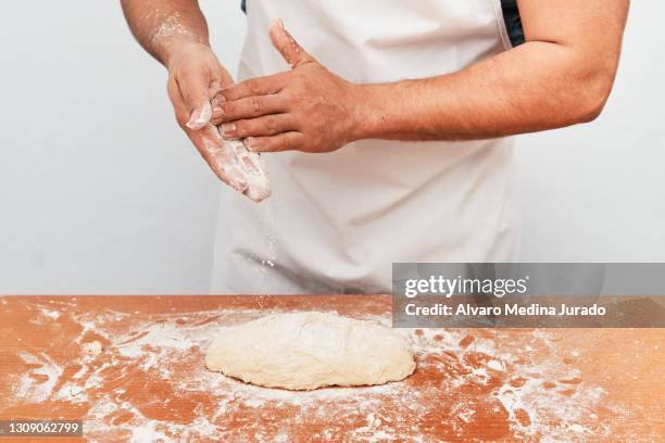 young baker pours flour over bread dough. - baker hands stock pictures, royalty-free photos & images