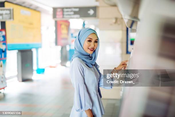 portrait of cheerful malaysian woman using atm - islamic finance stock pictures, royalty-free photos & images