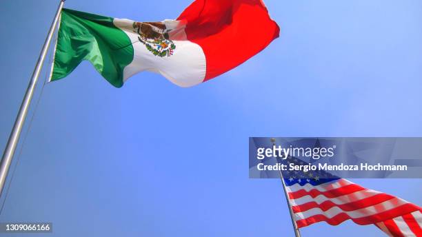 the american and mexican flags seen from a low angle against a blue sky - pact for mexico stock pictures, royalty-free photos & images