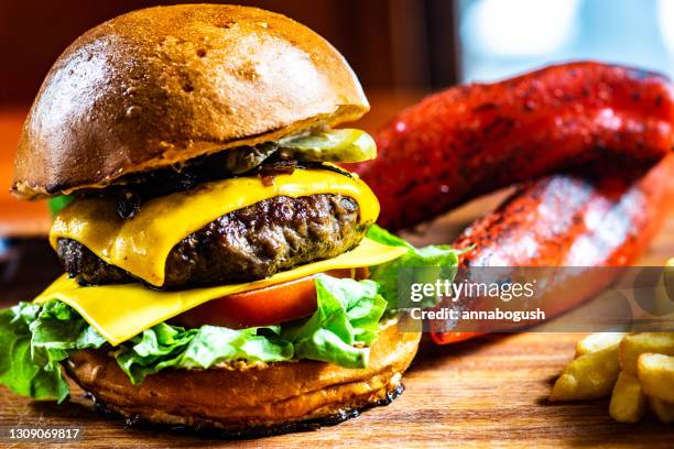 close-up of a cheeseburger with tomato, gherkin and lettuce served with fries and roasted red peppers - cheeseburger and fries stock-fotos und bilder