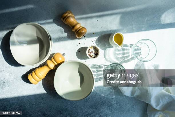 overhead view of crockery, glasses and seasoning on a table in the sunlight - pepper mill stock pictures, royalty-free photos & images