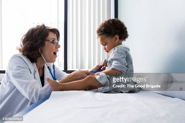 female doctor examining baby girl with stethoscope - pediatric imagens e fotografias de stock
