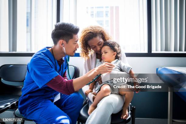 male nurse examining baby girl with stethoscope in hospital - pédiatre photos et images de collection