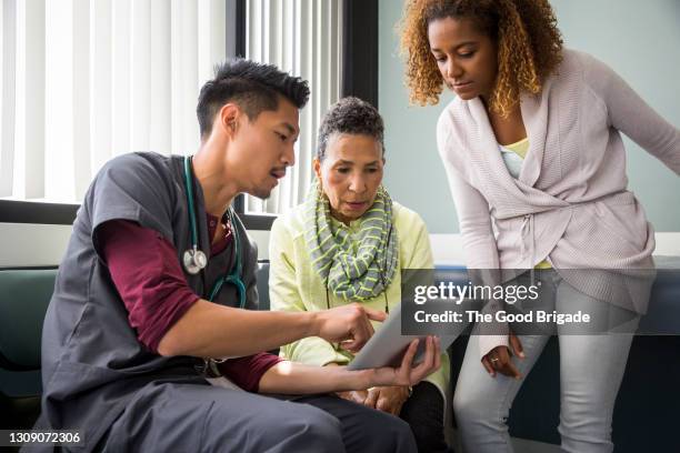 male nurse consulting with senior female patient and adult daughter in exam room - african american man helping elderly bildbanksfoton och bilder