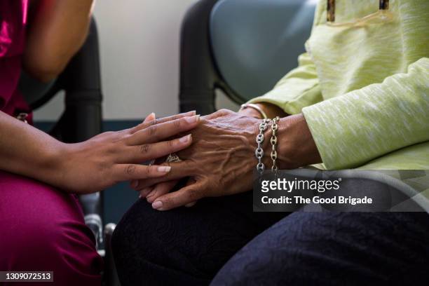 midsection of nurse consoling senior female in hospital - african american hand stock-fotos und bilder