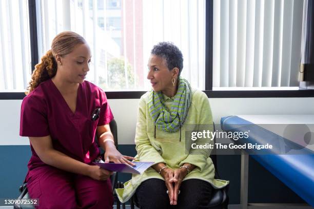 smiling senior woman talking to female nurse in hospital - nurse talking stock pictures, royalty-free photos & images