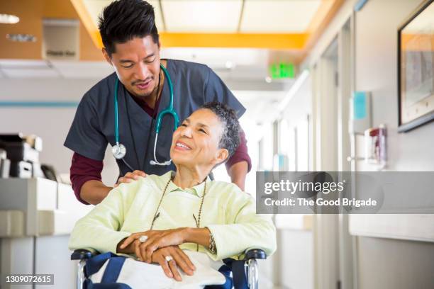 male nurse pushing senior woman in wheelchair - happy patient fotografías e imágenes de stock