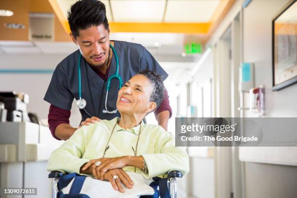 male nurse pushing senior woman in wheelchair - nurse and patient stockfoto's en -beelden
