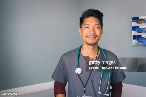 portrait of nurse with stethoscope standing against wall in hospital - medical scrubs - fotografias e filmes do acervo