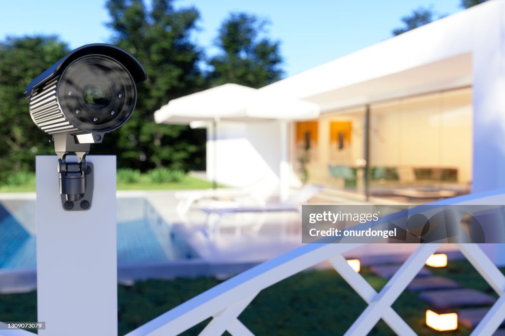 Esterno di una villa con telecamera di sicurezza all'ingresso del giardino.
